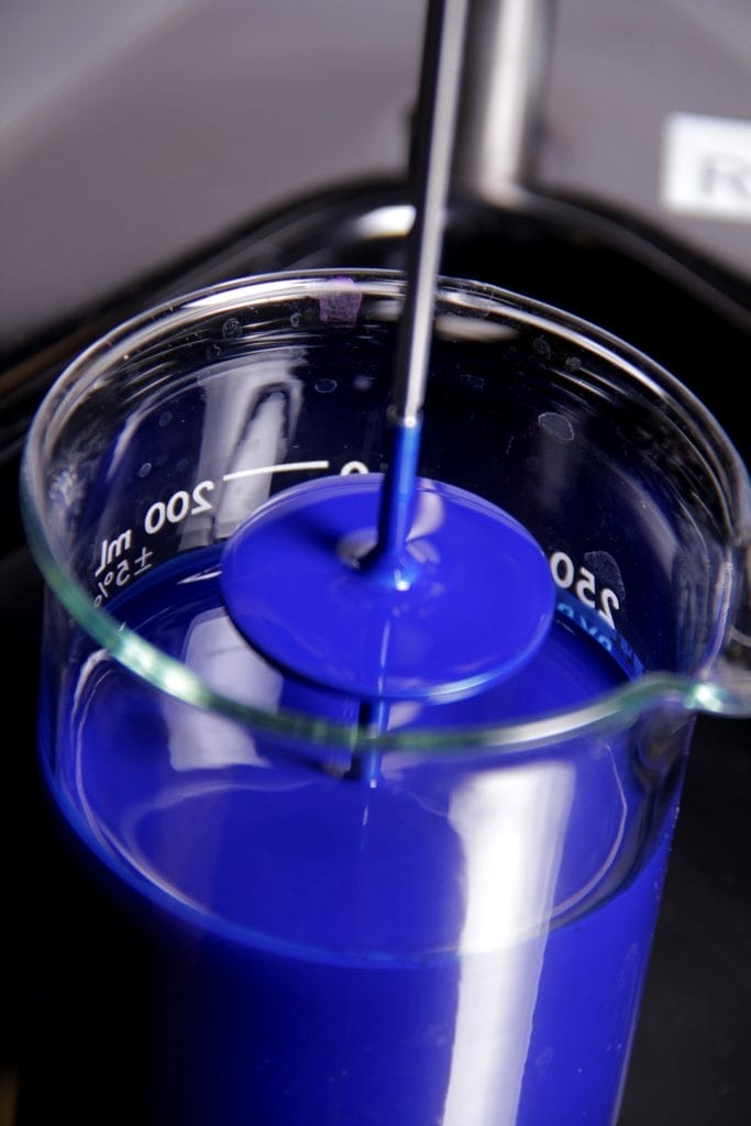 Blue pigment being blended into a coating resin in a laboratory beaker